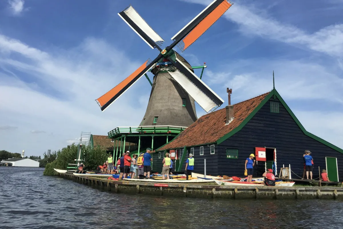 Een windmolen en een groen Zaans pakhuis aan de Zaan bij de Zaanse Schans in Zaandam